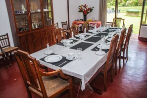 Een eethoek met een lange tafel gedekt voor een maaltijd, omringd door houten stoelen.