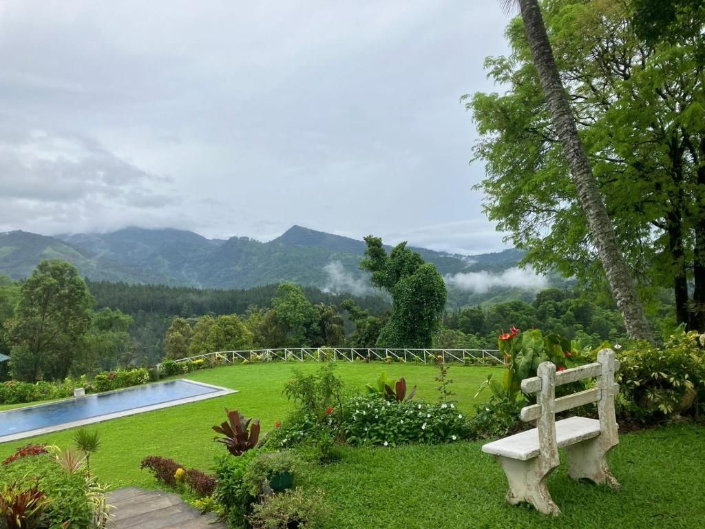 Un jardin luxuriant avec une piscine, un banc et une vue sur les montagnes.