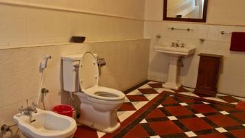A bathroom with a toilet, bidet, sink, and a mirror.