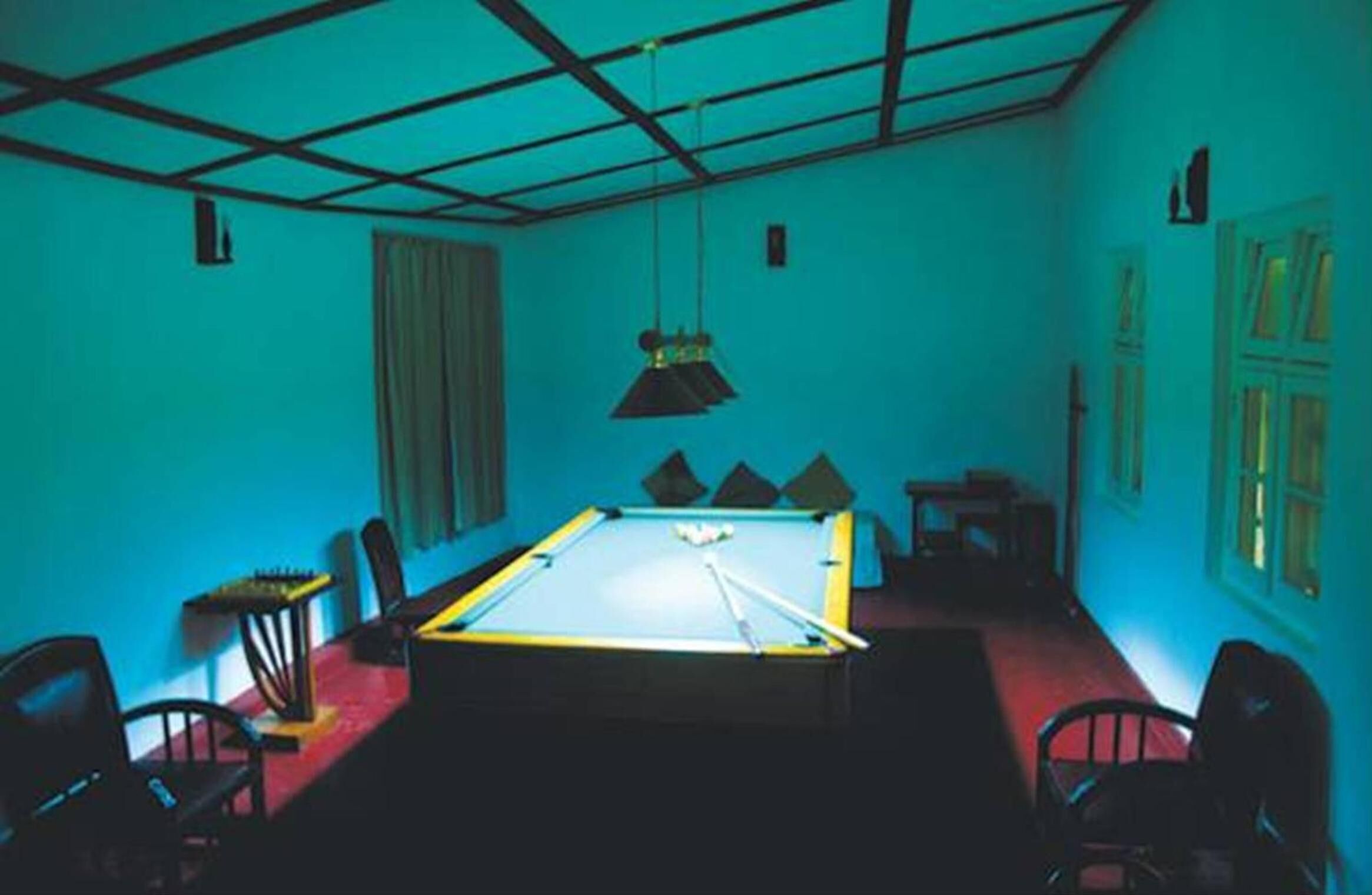 A room with a pool table, chairs, and a hanging light fixture.