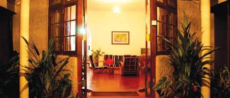 A warmly lit hallway with a red carpet leading to a seating area with a sofa and chairs.