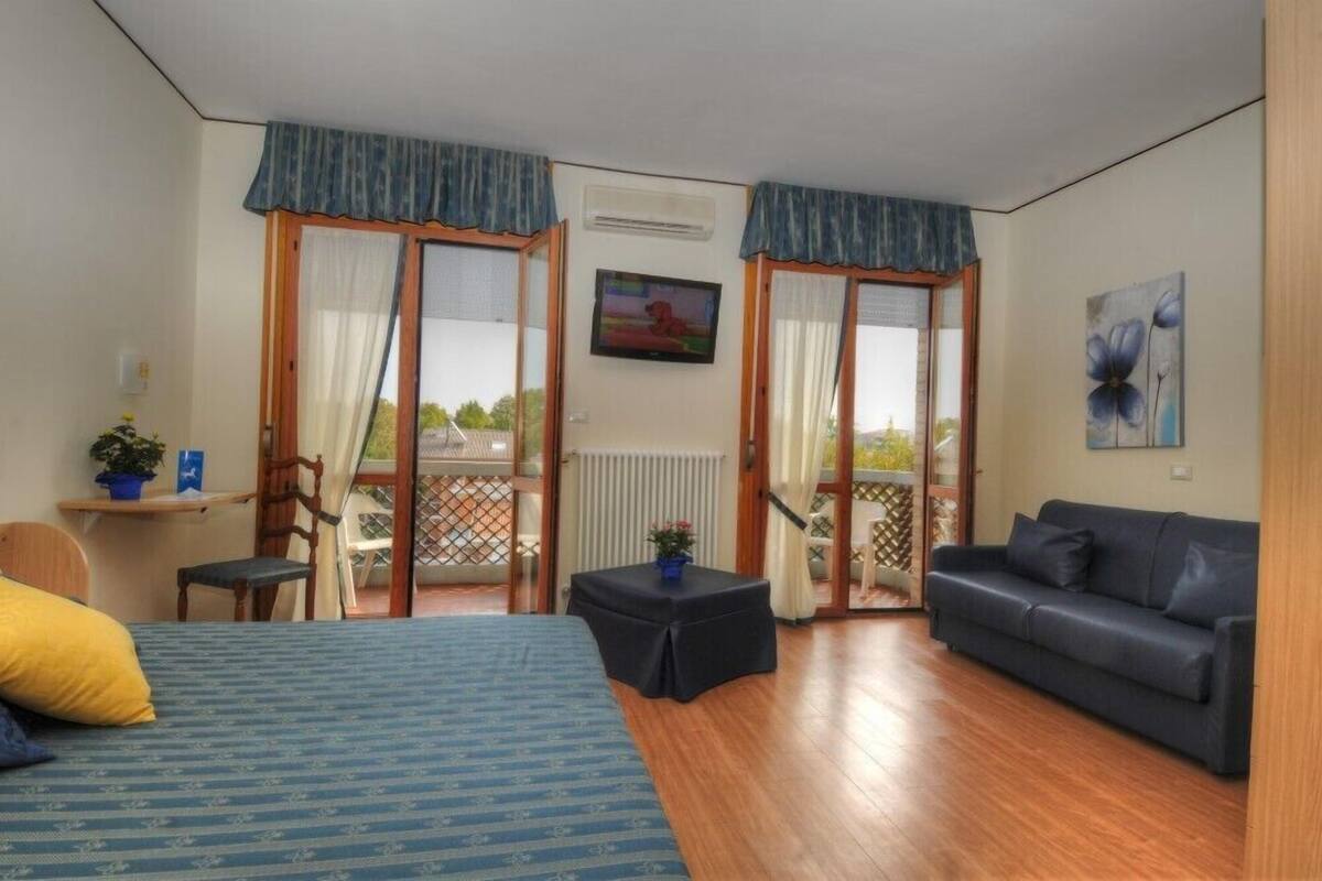 Une chambre avec un lit, un canapé, une petite table et un balcon avec vue.