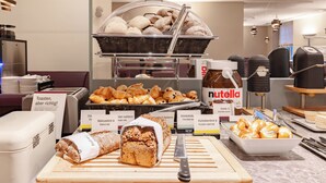 A buffet with various baked goods, including bread, pastries, and a Nutella spread.