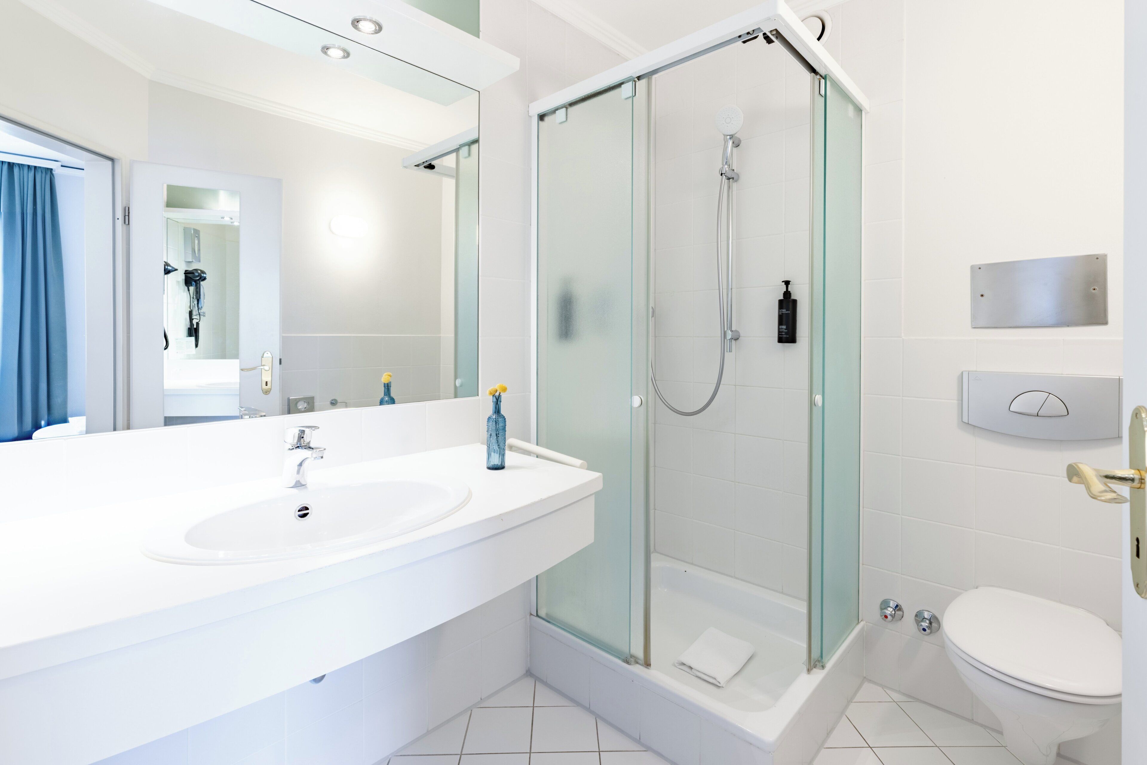 A modern bathroom with a glass-enclosed shower, a double sink vanity, and a toilet.
