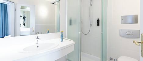 A modern bathroom with a glass-enclosed shower, a double sink vanity, and a toilet.