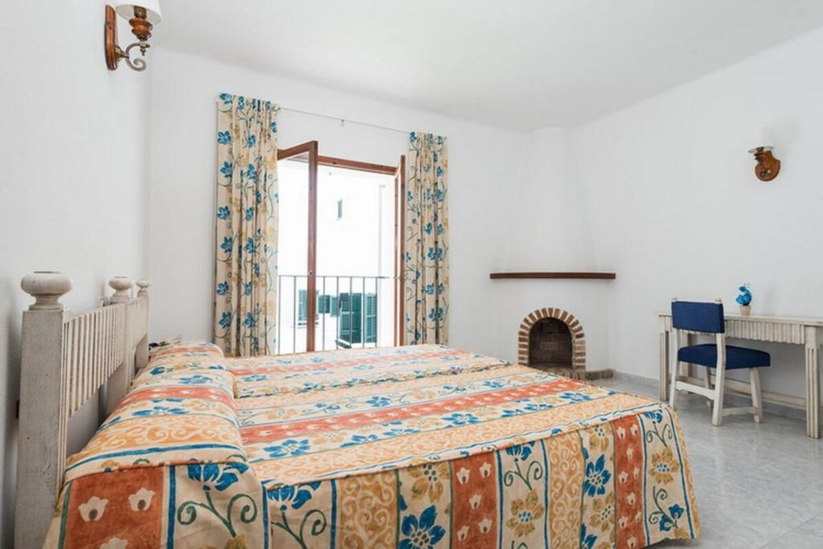 Un dormitorio con una cama grande, una chimenea, un escritorio y un balcón con cortinas.