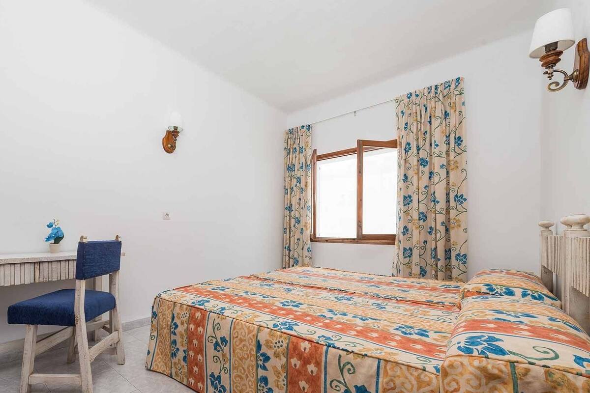 A bedroom with a bed, a desk, and a chair.