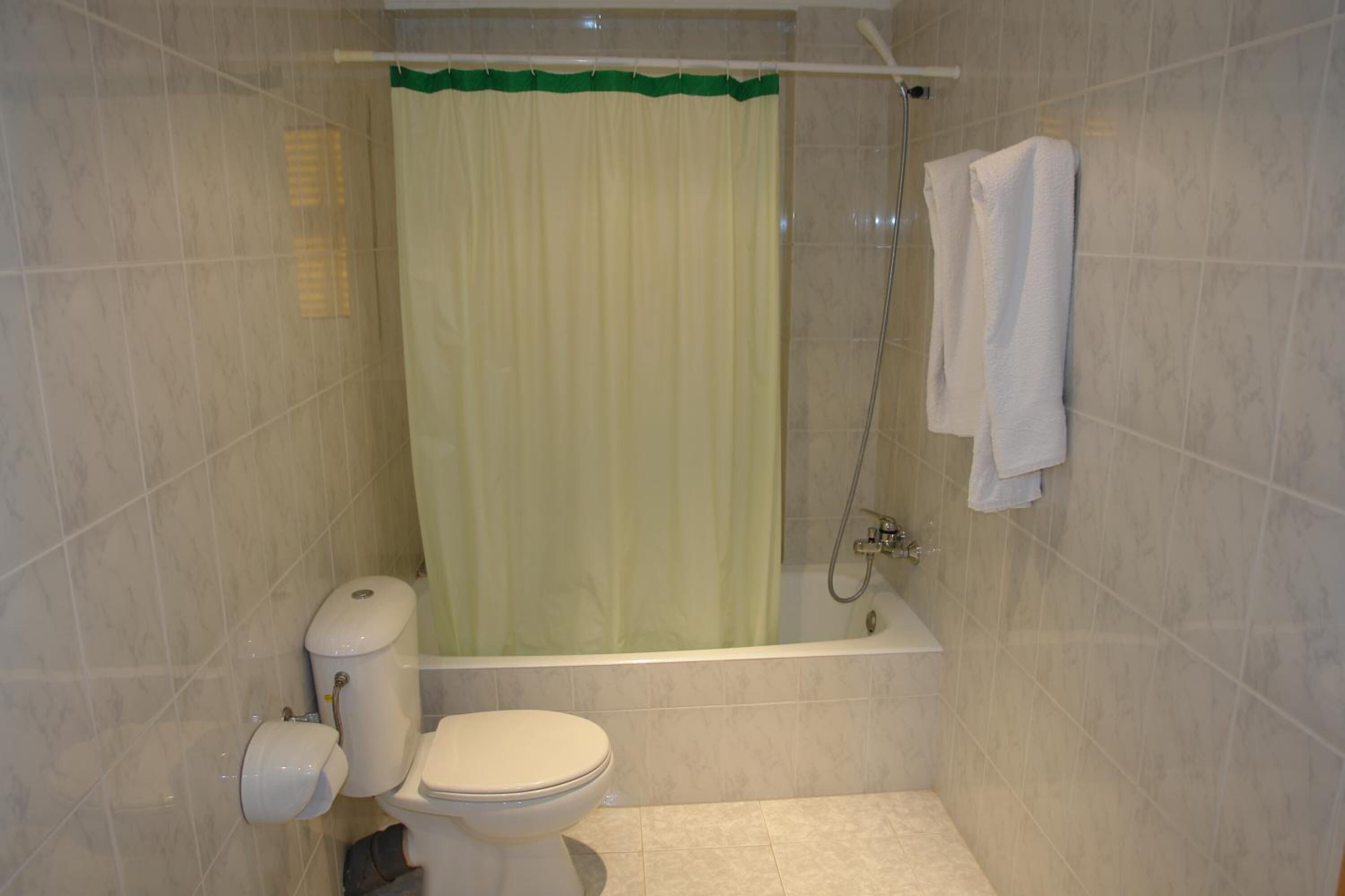 Een badkamer met een toilet, een bad en een douche.