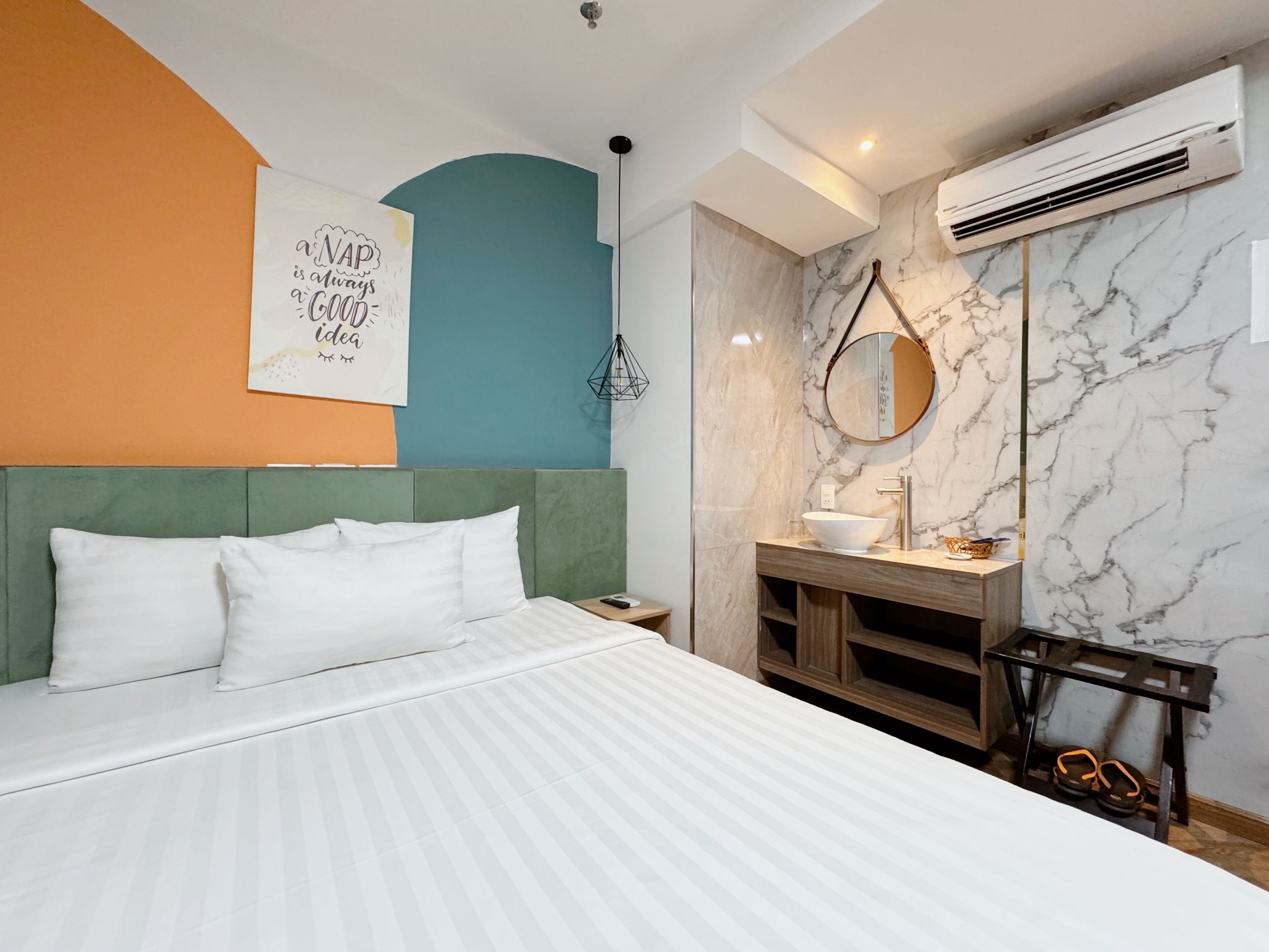 Una camera da letto moderna con un letto, un comodino, un lavabo in bagno e un condizionatore d'aria.