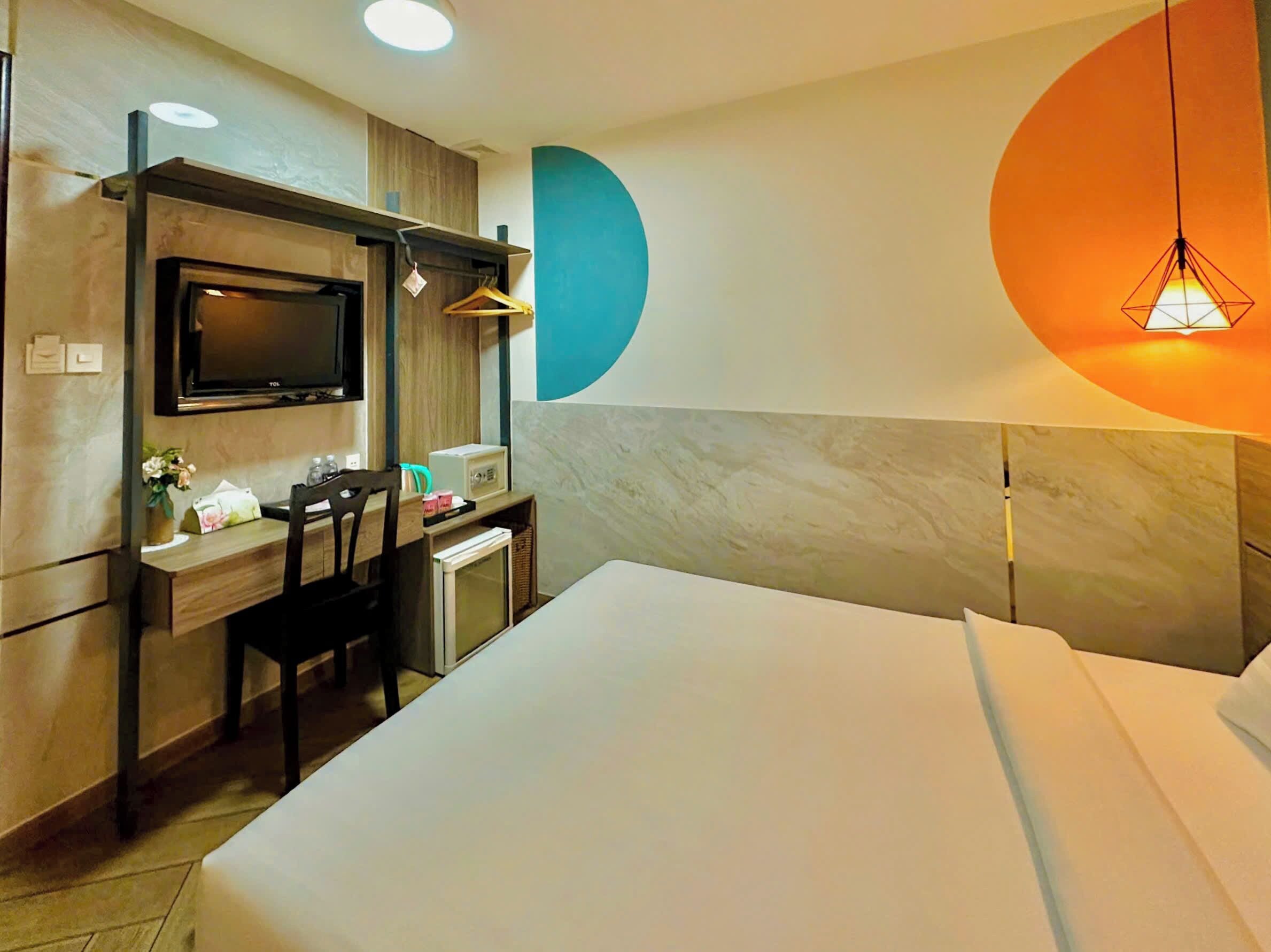 Ein Hotelzimmer mit einem Bett, einem Schreibtisch mit Stuhl, einem Fernseher und einer Mikrowelle.