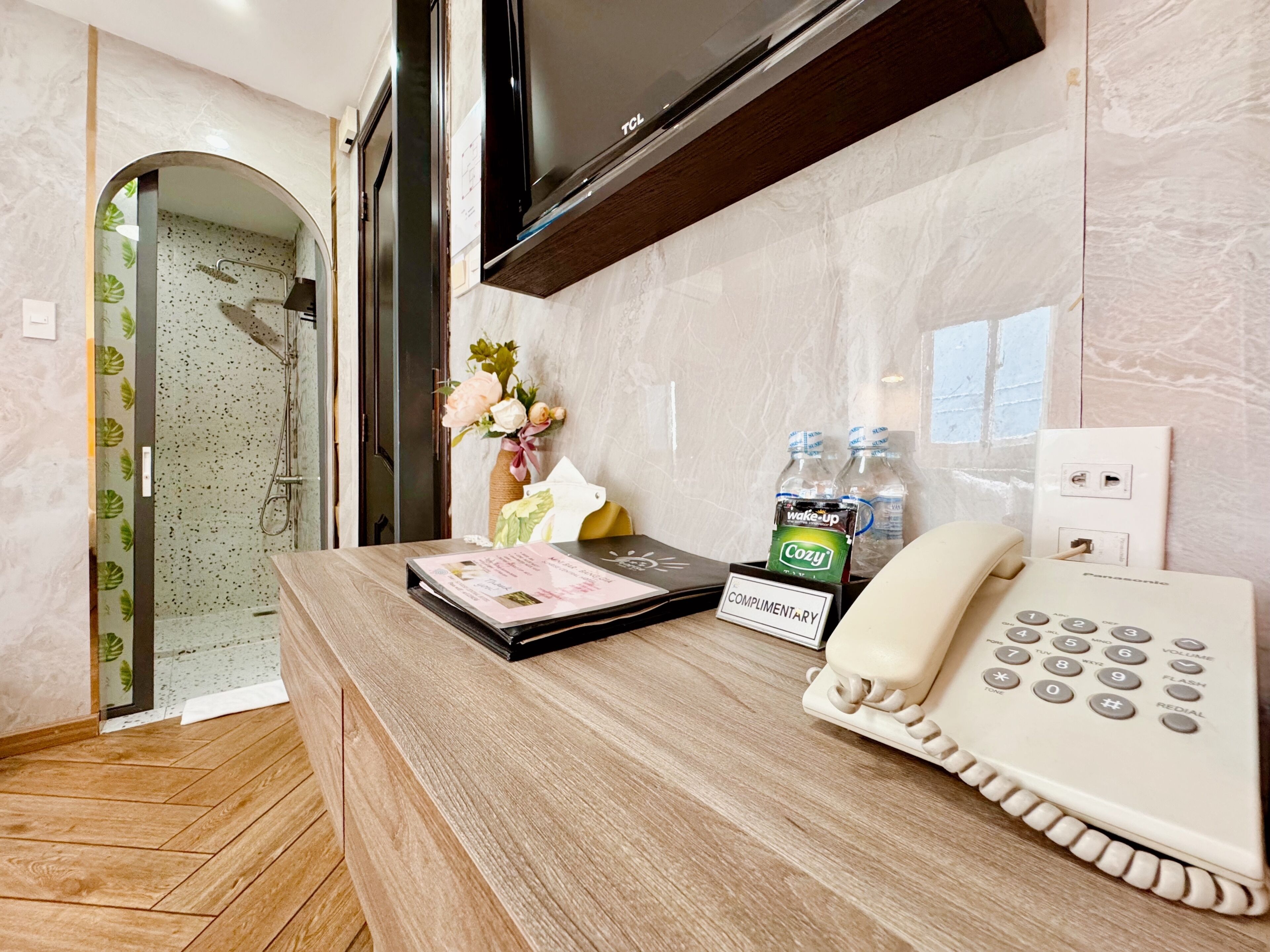 Ein Hotelrezeptionstresen mit Telefon, Speisekarte und Blumenvase.