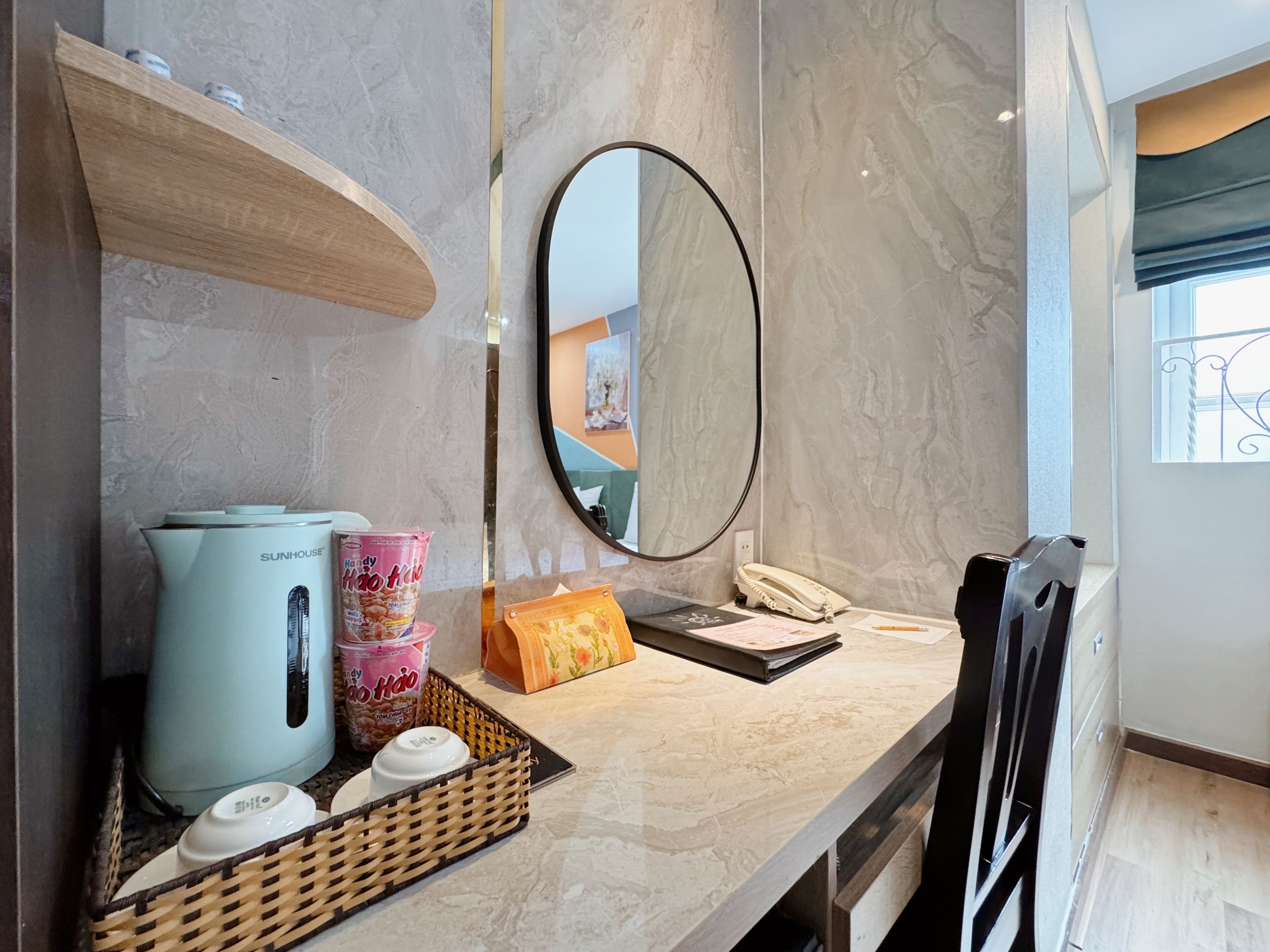 Une salle de bain moderne avec un comptoir en marbre, une bouilloire, un panier contenant des articles de toilette, un miroir et un téléphone.
