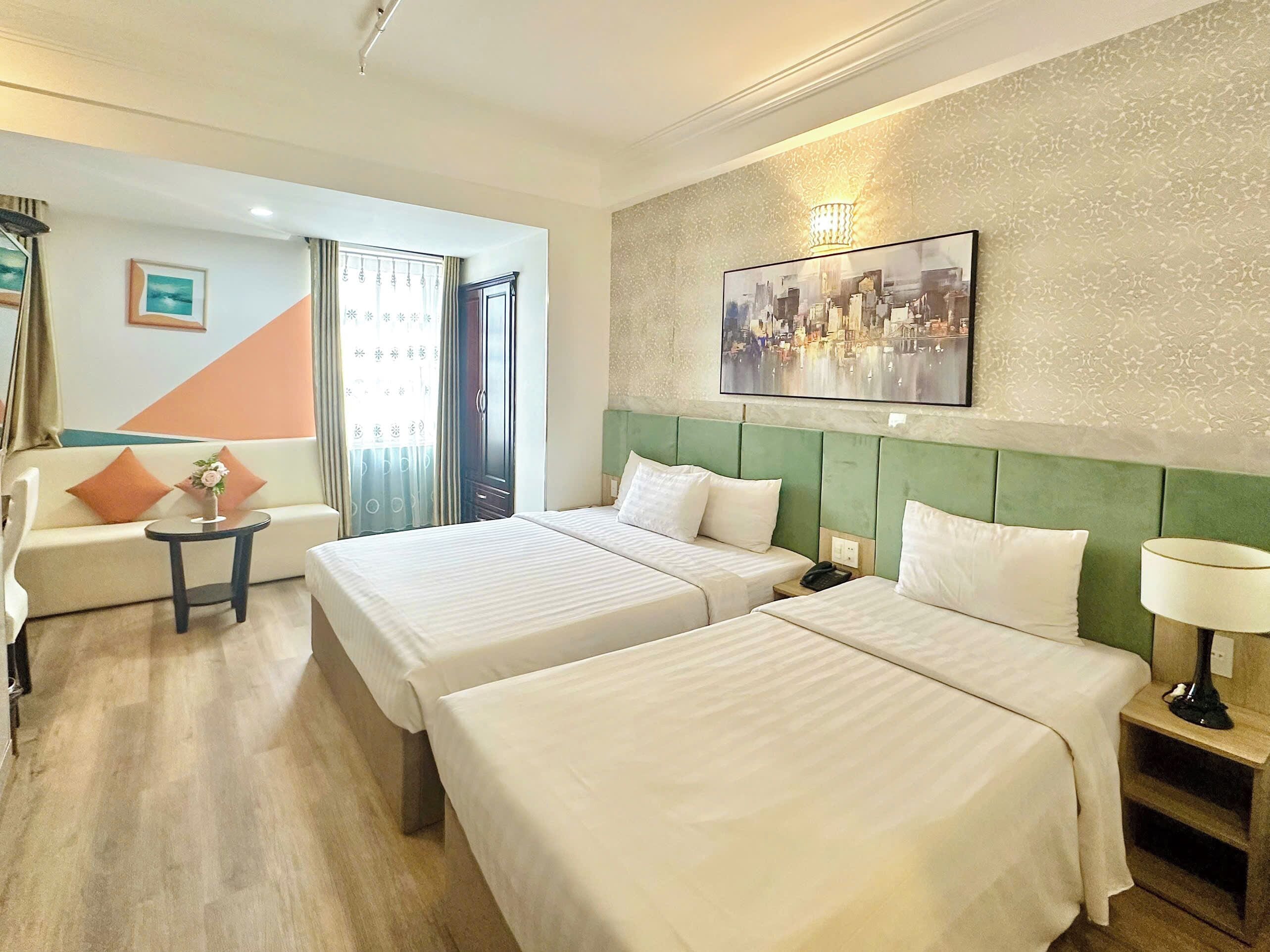 Une chambre d’hôtel avec deux lits, un canapé, une petite table et un tableau au mur.