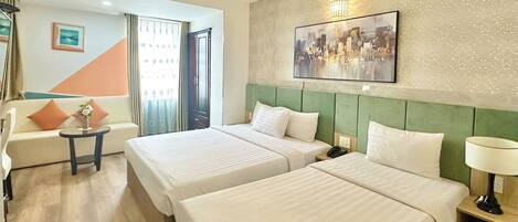Une chambre d’hôtel avec deux lits, un canapé, une petite table et un tableau au mur.
