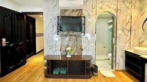 A modern bathroom with a marble wall, a mounted TV, and a vanity with a sink. - Sunrise Central Hotel (Ho Chi Minh City)