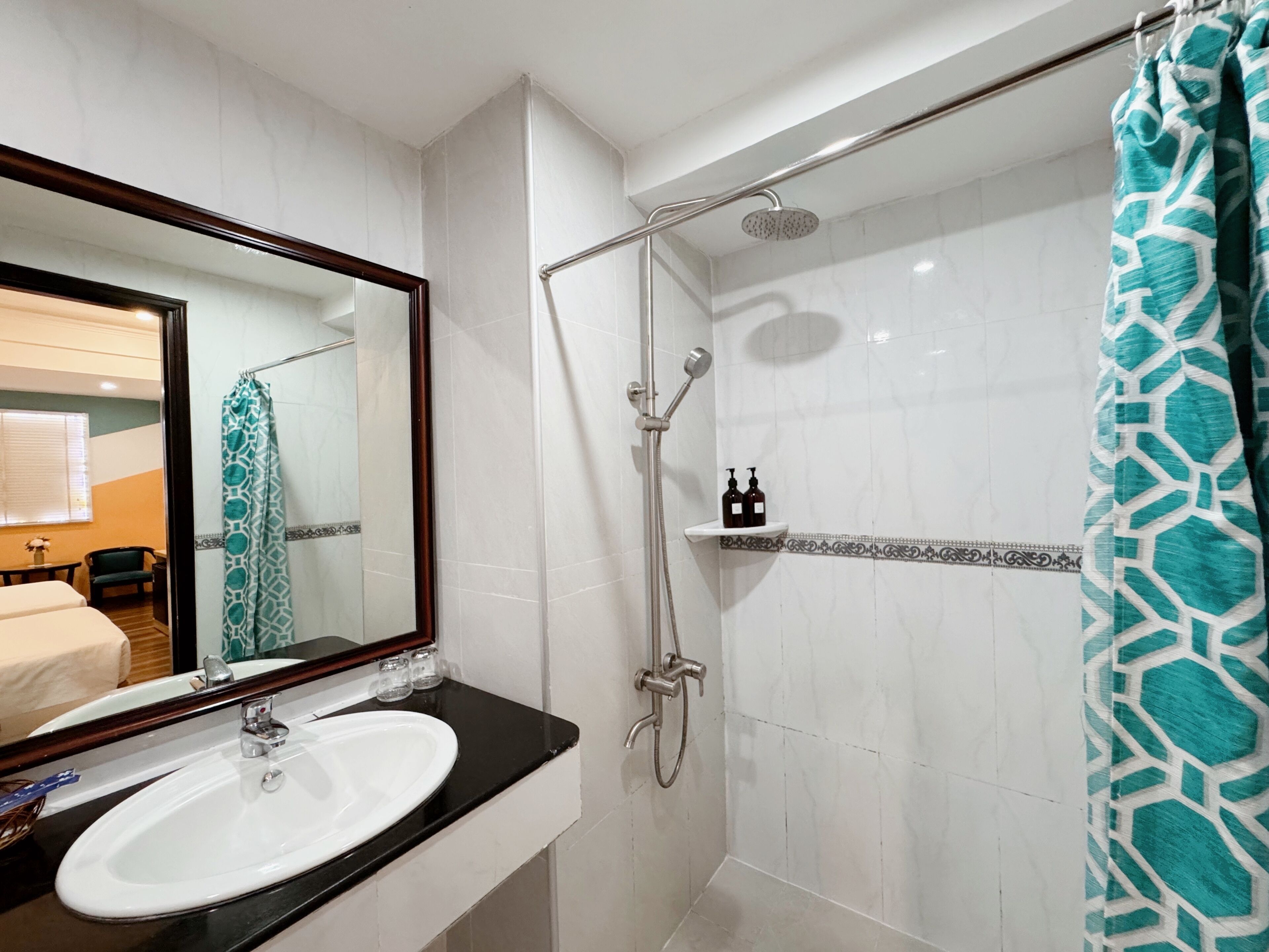 Un baño con un lavamanos blanco, un espejo, una ducha con cabezal de ducha manual y un perchero para toallas.