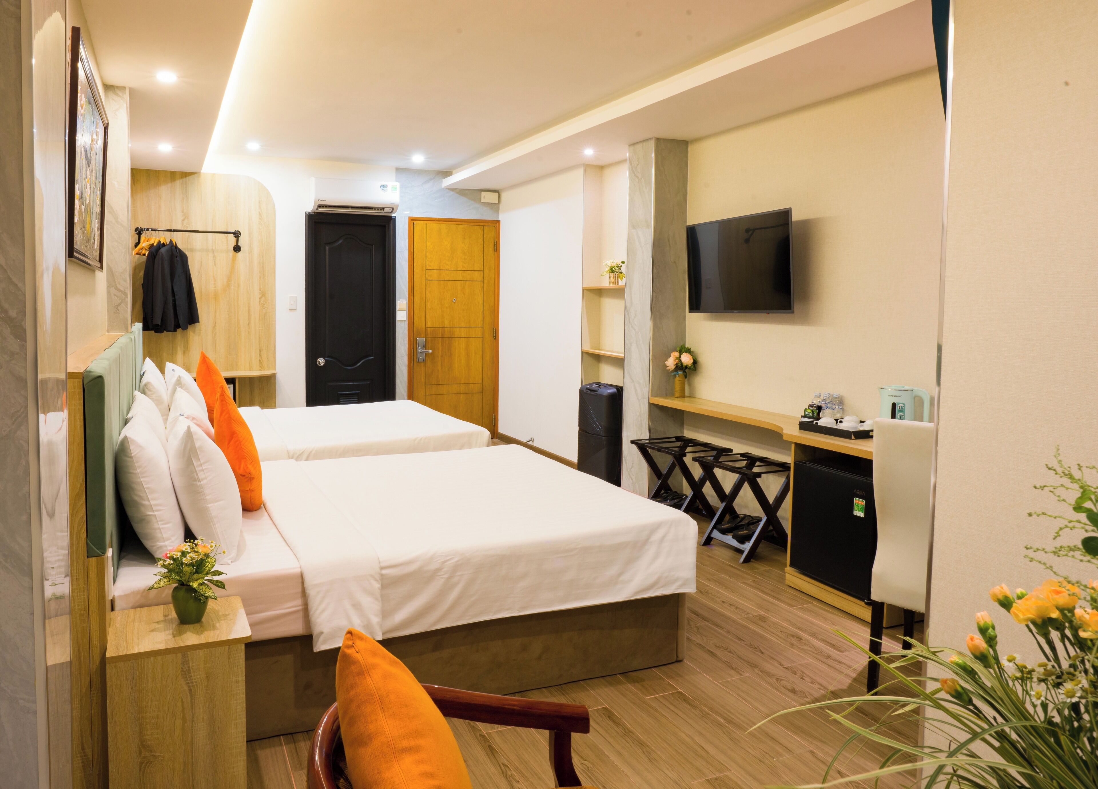 A hotel room with two beds, a desk, a TV, and a trash bin.
