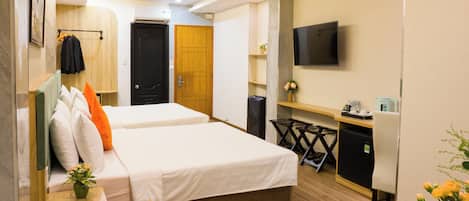 A hotel room with two beds, a desk, a TV, and a trash bin.