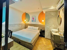 A modern hotel room with a large bed, a bedside table, a nightstand, a bathroom with a sink and mirror, and a unique circular wall design.