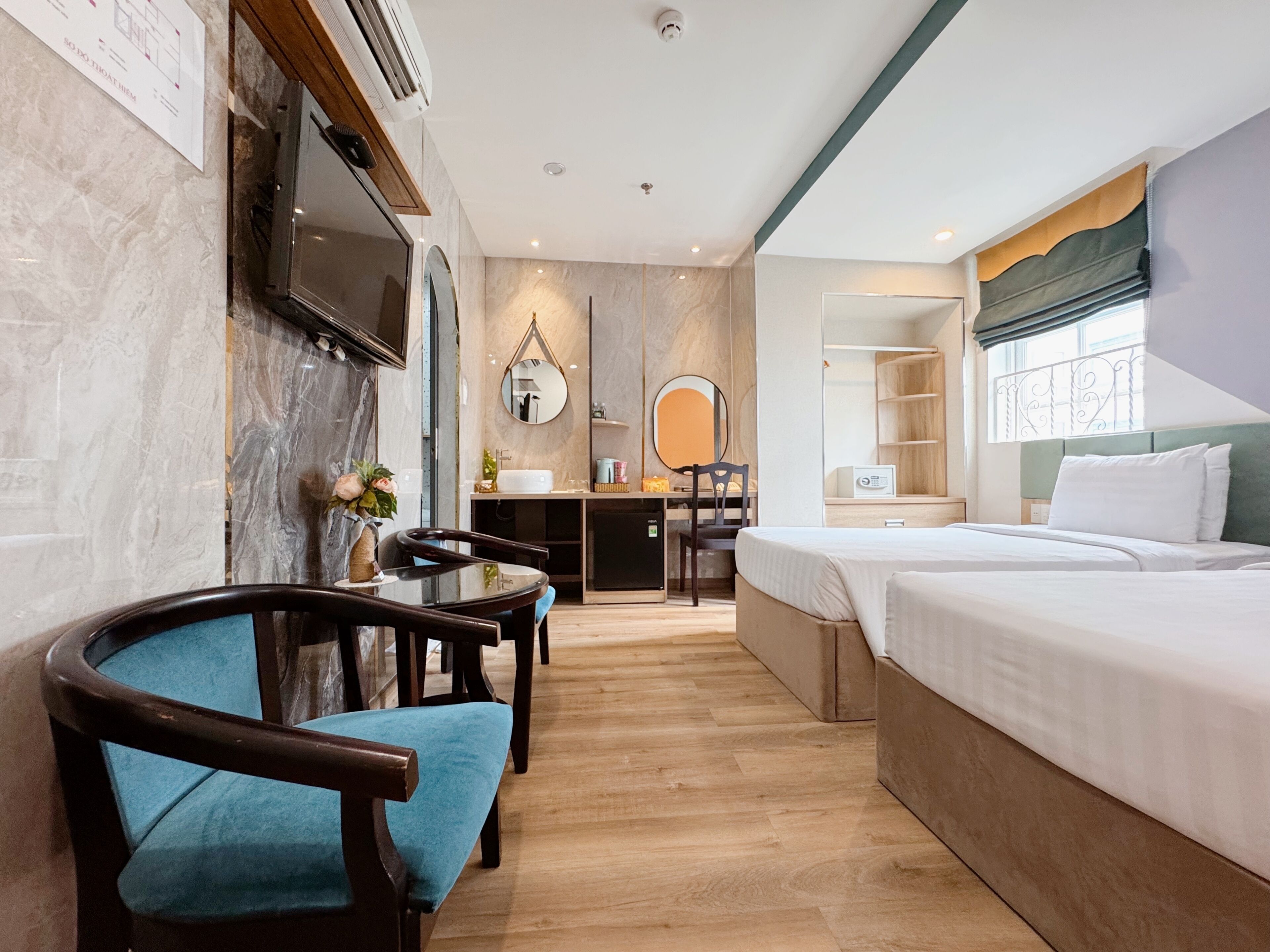A hotel room with a bed, a desk, a chair, a mirror, and a television.