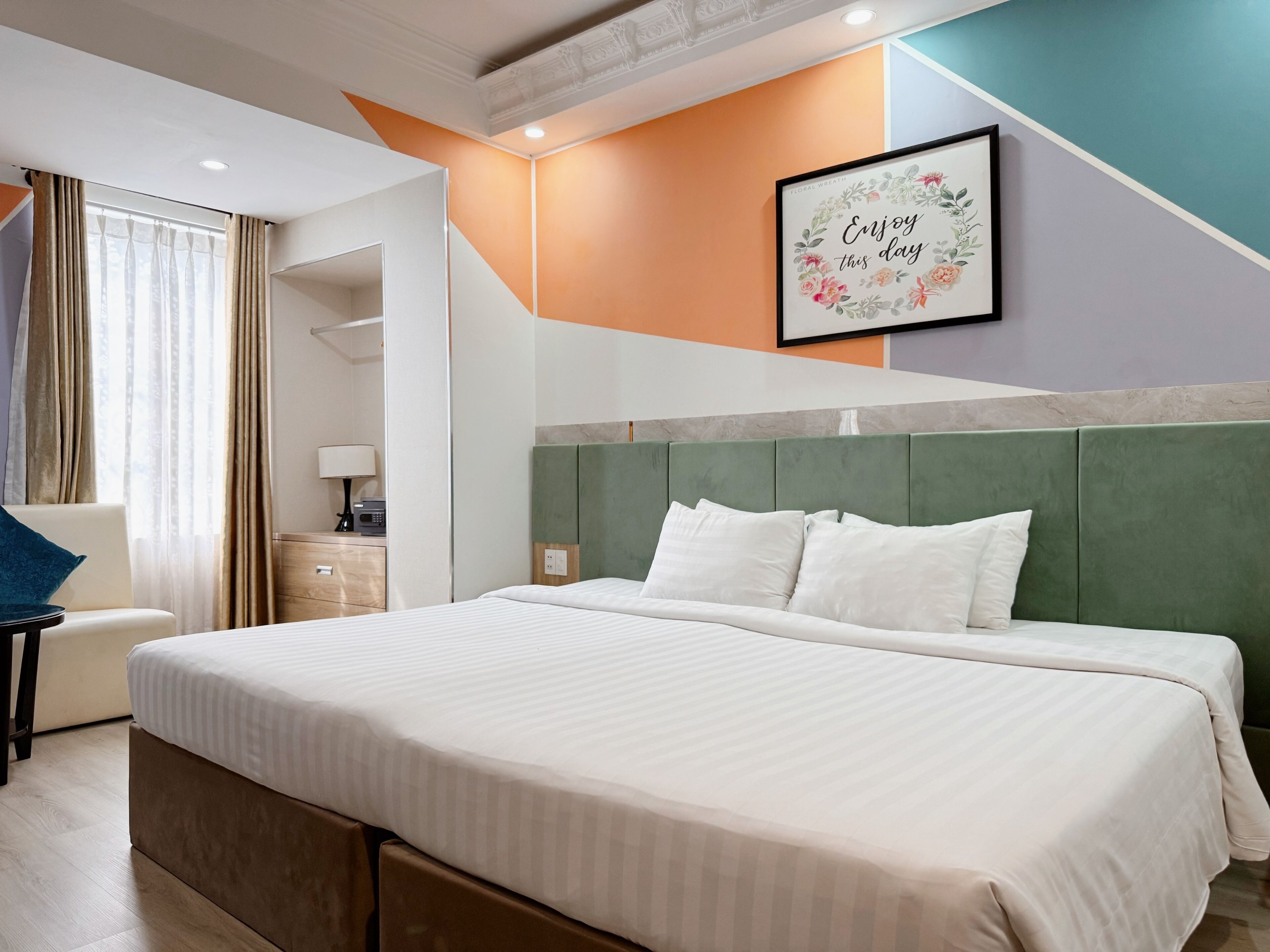 A hotel room with a large bed, a desk, a chair, and a framed motivational quote on the wall.