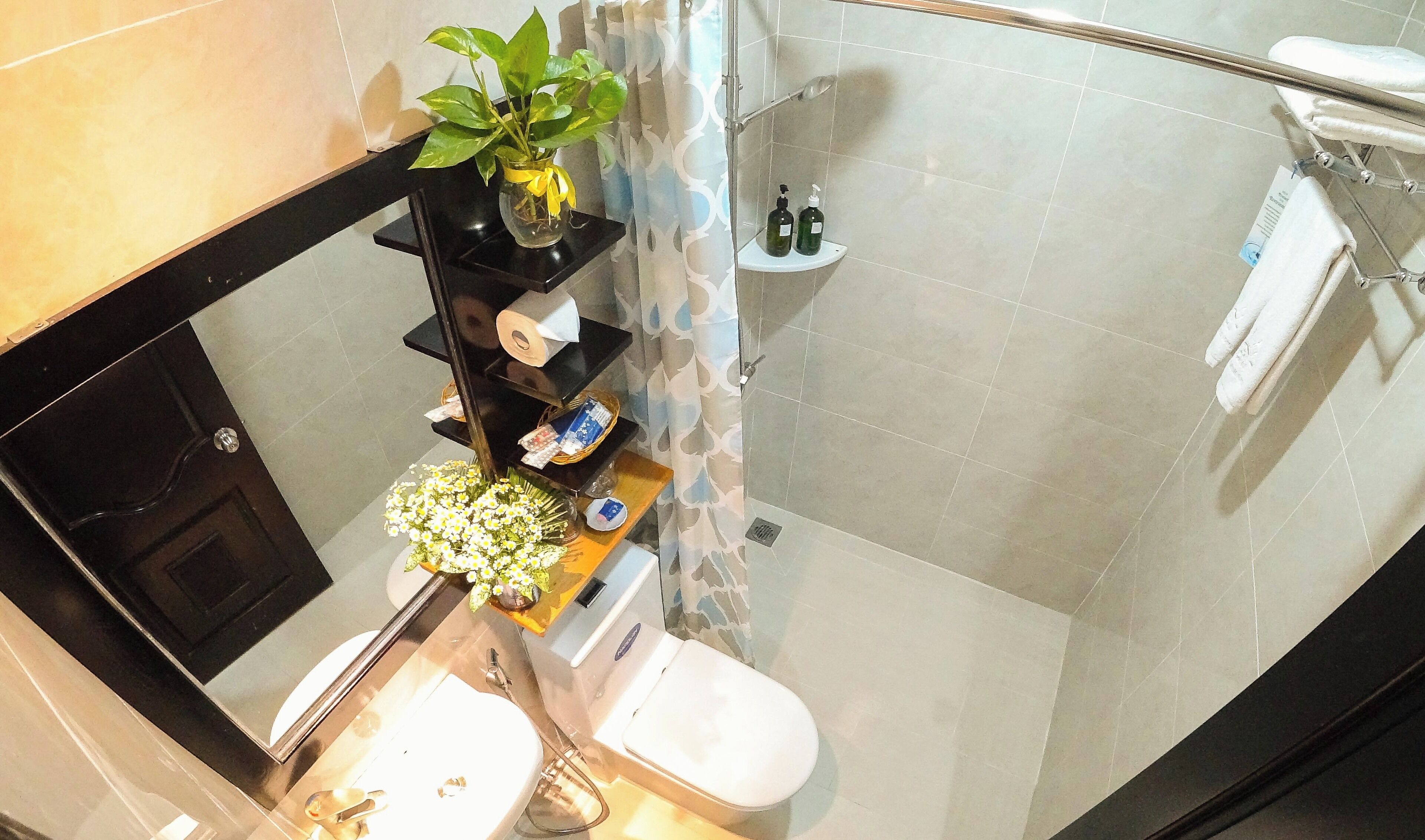 Une salle de bain équipée de toilettes, d’un lavabo, d’une douche et d’une étagère où sont rangés les articles de toilette.