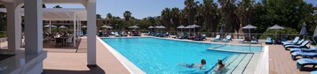 Una piscina al aire libre, sombrillas, tumbonas