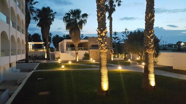 A modern building with a courtyard, palm trees, and outdoor lighting. - Cosmopolitan Kos Hotel (Kos)