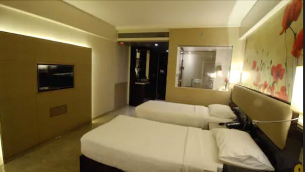 Camera d'albergo con due letti, una TV, uno specchio e un ingresso che porta al bagno.