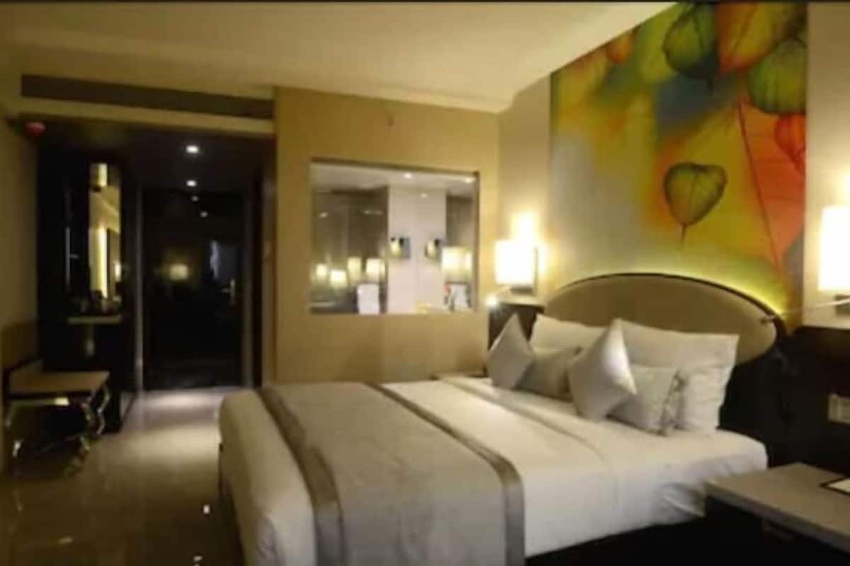 Una habitación de hotel con cama, mesita de noche y un cuadro en la pared.