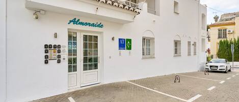 A white building with a sign reading 'Almoraide,' a parking sign, and a white car parked in front.