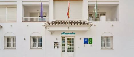 Um edifício com fachada branca, telhado em telhas e uma placa com a inscrição 'Almoraide'.