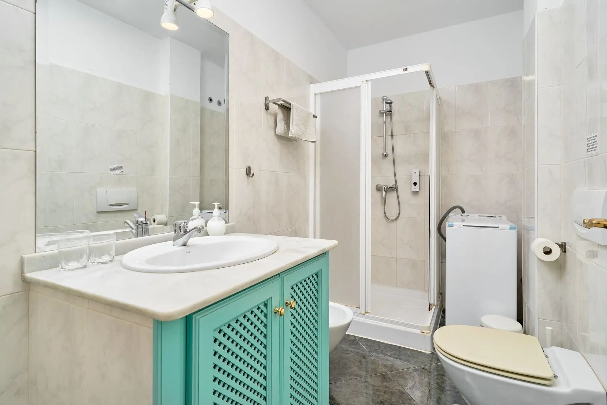 A bathroom with a white sink, a mirror, a shower, and a toilet.
