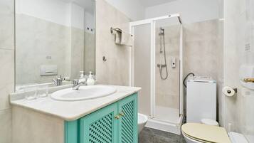 A bathroom with a white sink, a mirror, a shower, and a toilet.