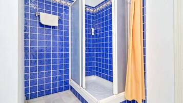 Ein Badezimmer mit blauen Fliesen, einer Dusche und einem orangefarbenen Duschvorhang.