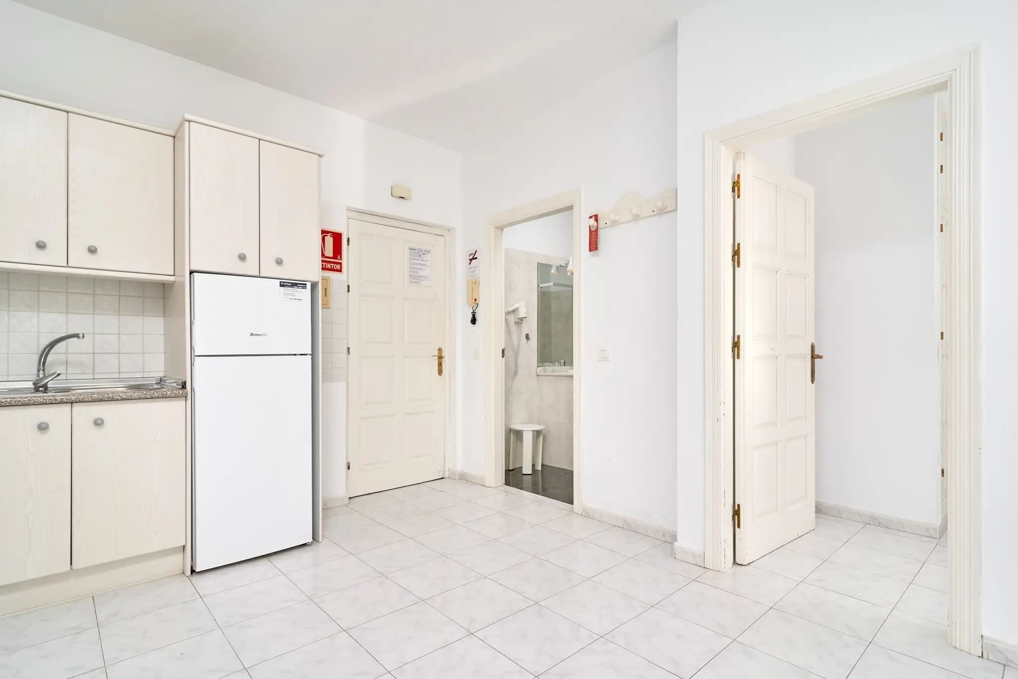 A kitchen with white cabinets, a white refrigerator, and a tiled floor.