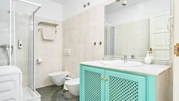 Une salle de bain avec une douche à parois de verre, des toilettes, un lavabo avec un miroir et un meuble avec un motif en treillis.