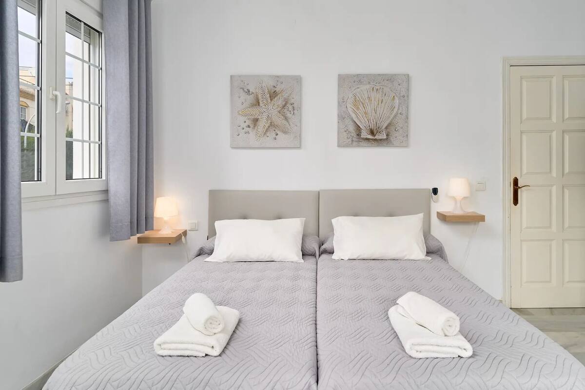 A double bed with two pillows, a bedside table with a lamp, and two wall art pieces.