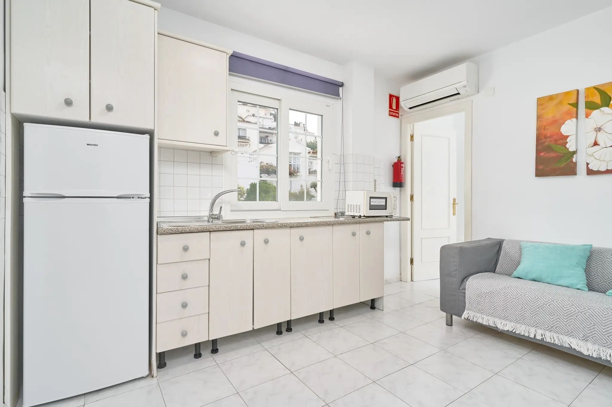 A modern kitchen with white cabinets, a built-in oven, and a window.
