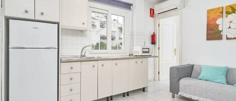 Una cocina moderna con armarios blancos, horno empotrado y ventana.