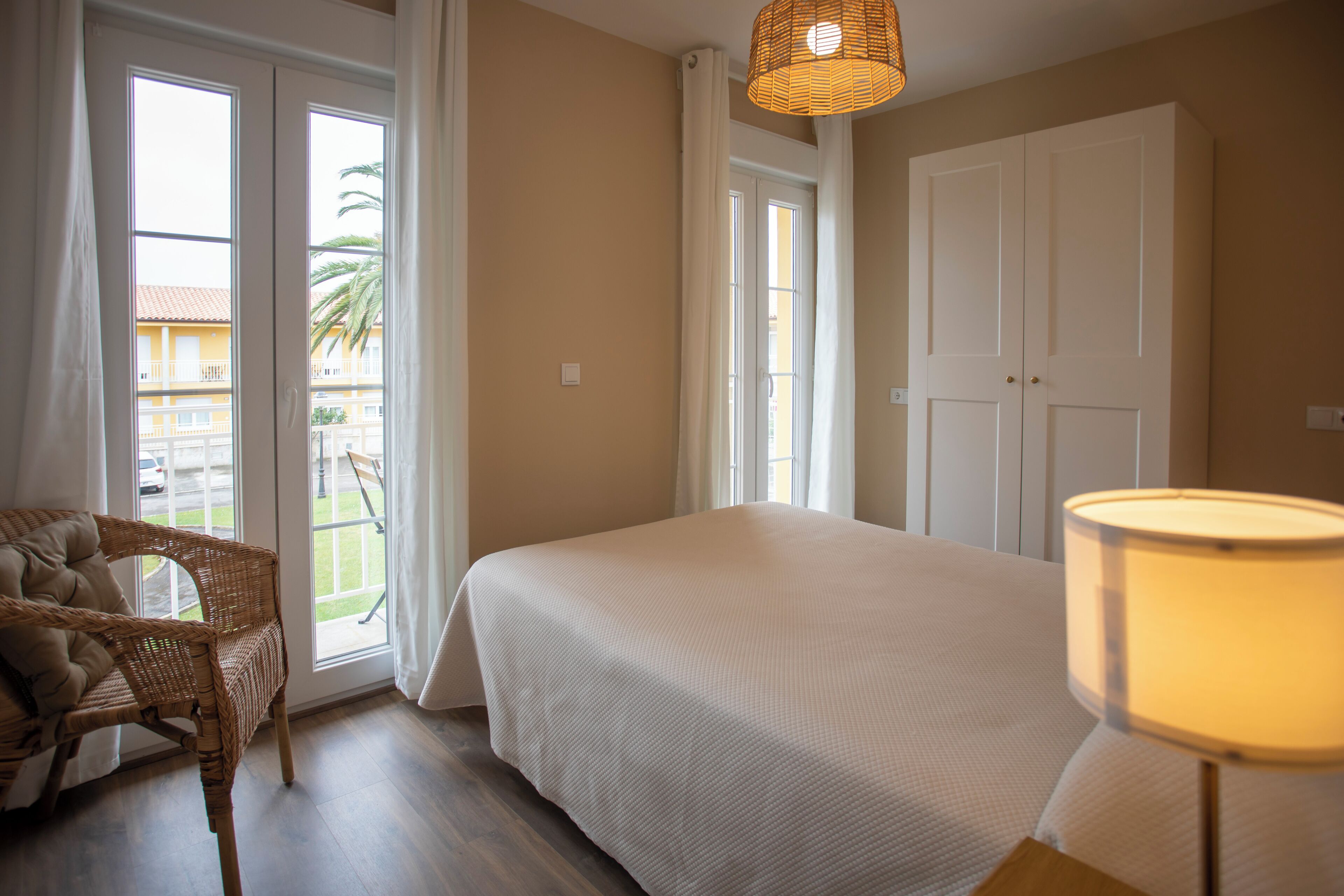 Un dormitorio con cama, una silla, una lámpara y una puerta.