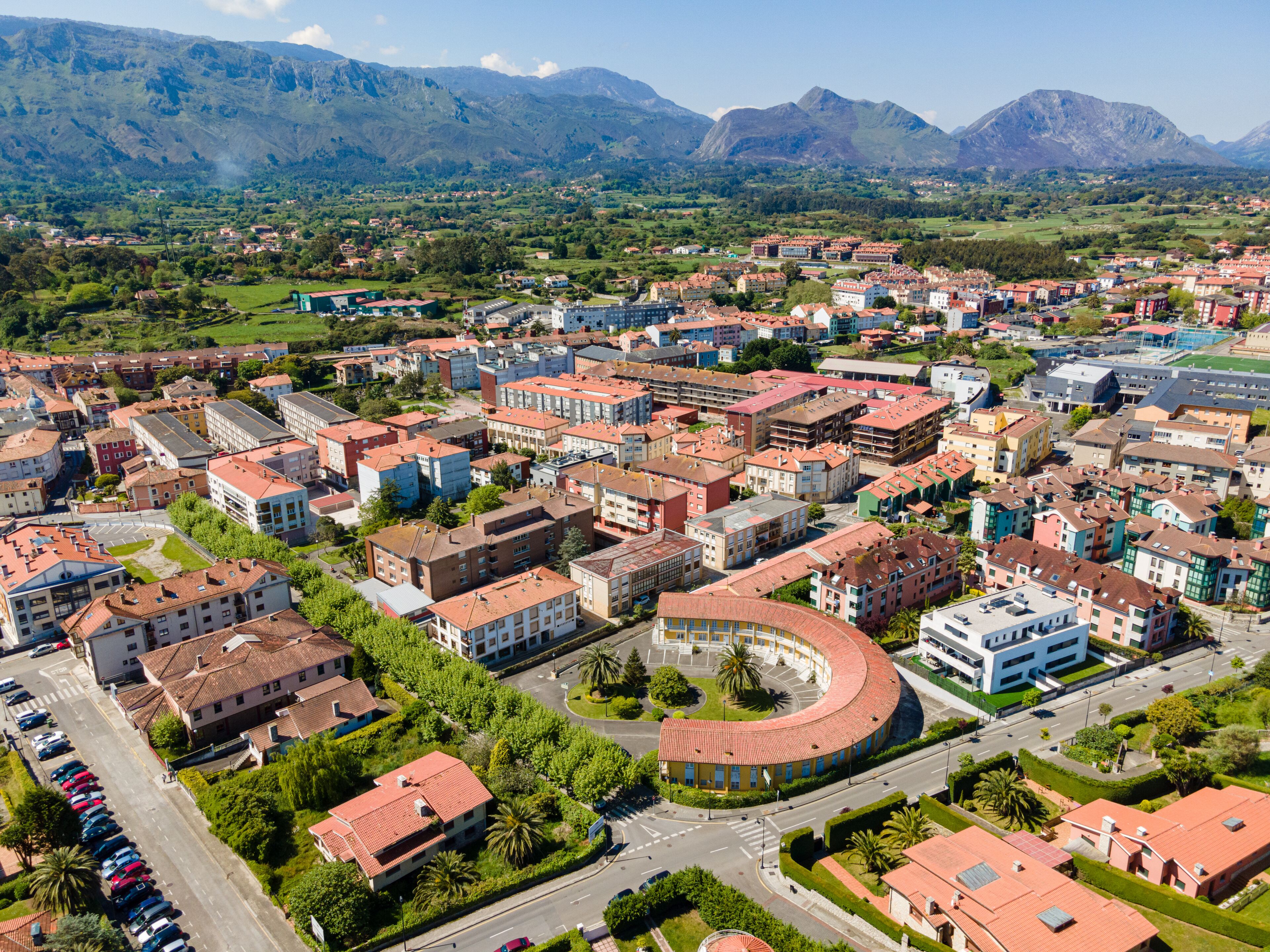 An aerial view of a town with a mix of residential and commercial buildings, surrounded by mountains.