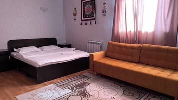 A bedroom with a bed, a sofa, a radiator, and a decorative rug.
