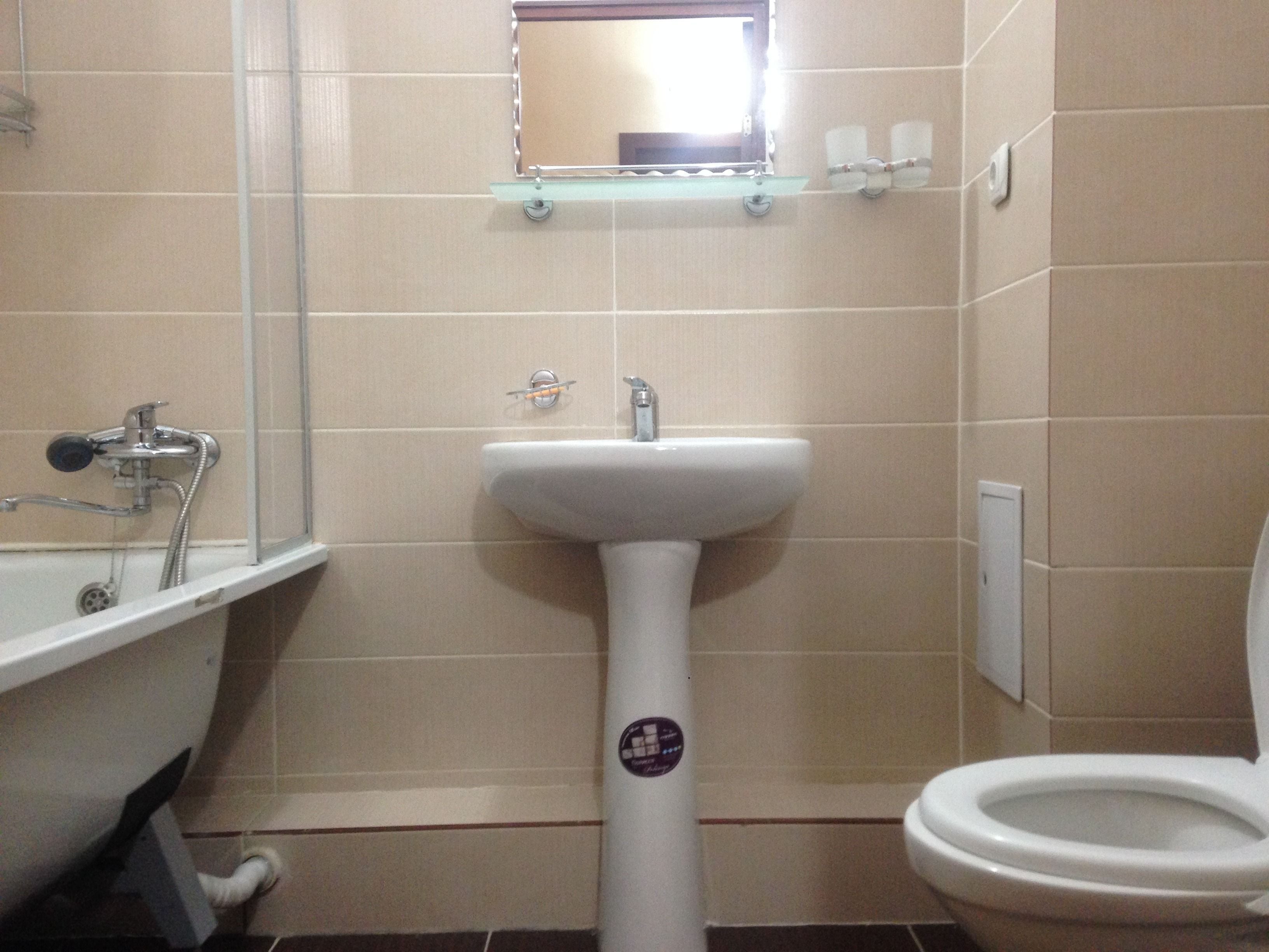 Ein Badezimmer mit weißem Waschbecken, einem Spiegel, einer Toilette und einer Duschkabine.