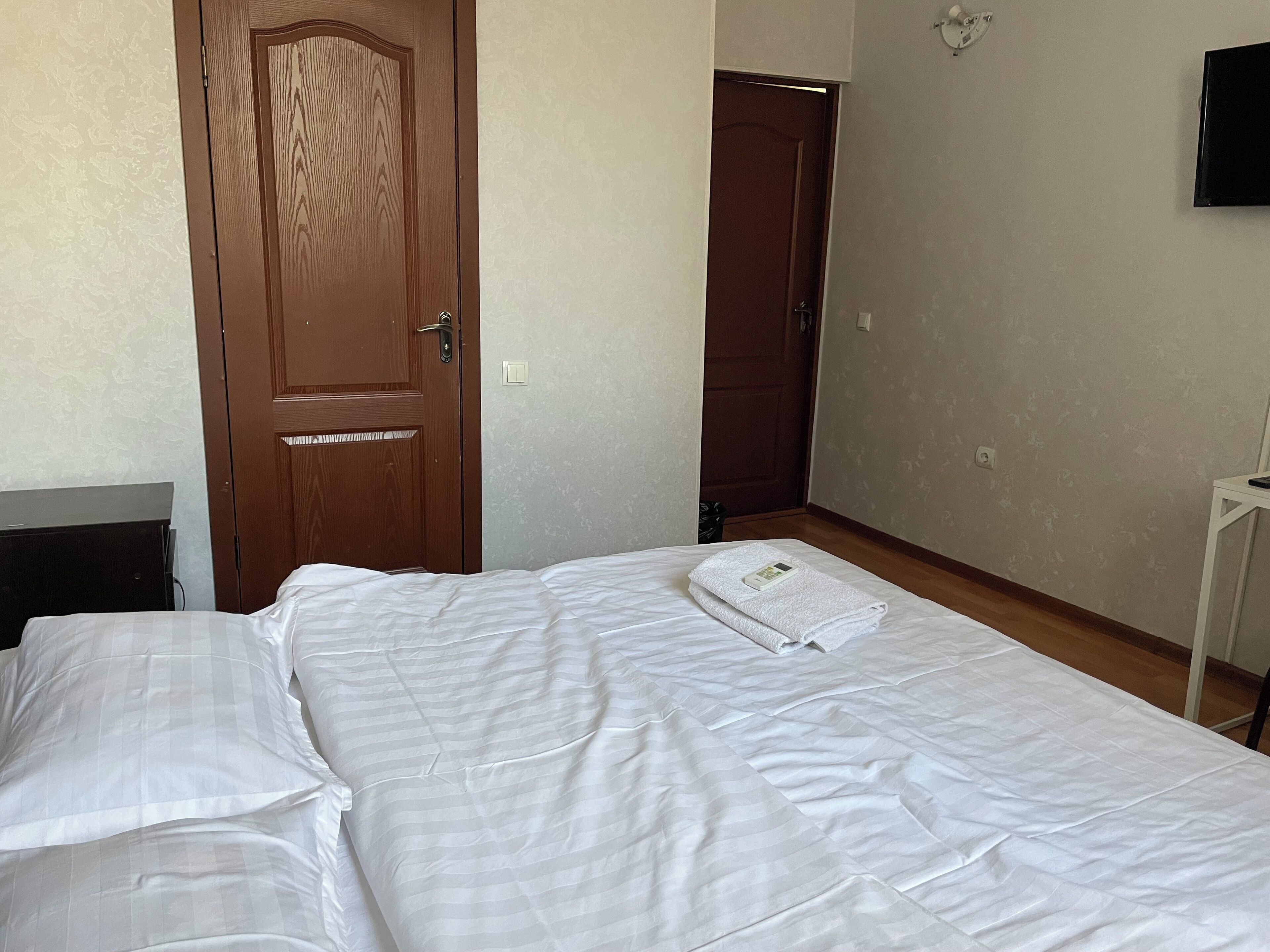 Un dormitorio con una cama, una puerta de madera y un televisor en la pared.