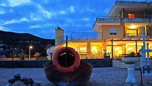 Un edificio costero con una estructura circular destacada al frente, posiblemente un flotador de rescate, y una entrada bien iluminada con un balcón.