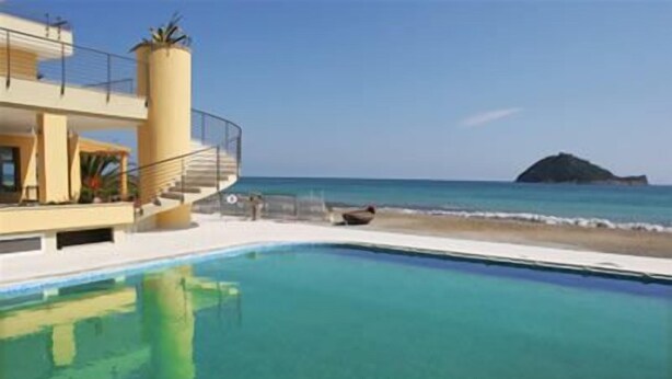 Zona de piscina con vista despejada al océano y una isla distante.
