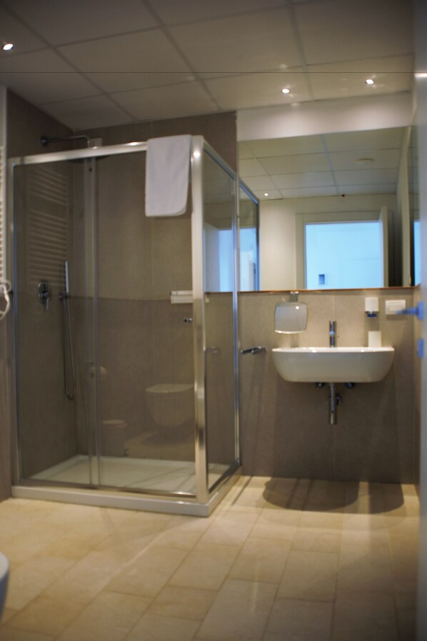 A modern bathroom with a glass-enclosed shower, a sink, and a mirror.