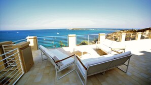 Une terrasse avec deux fauteuils blancs et une vue sur la mer.
