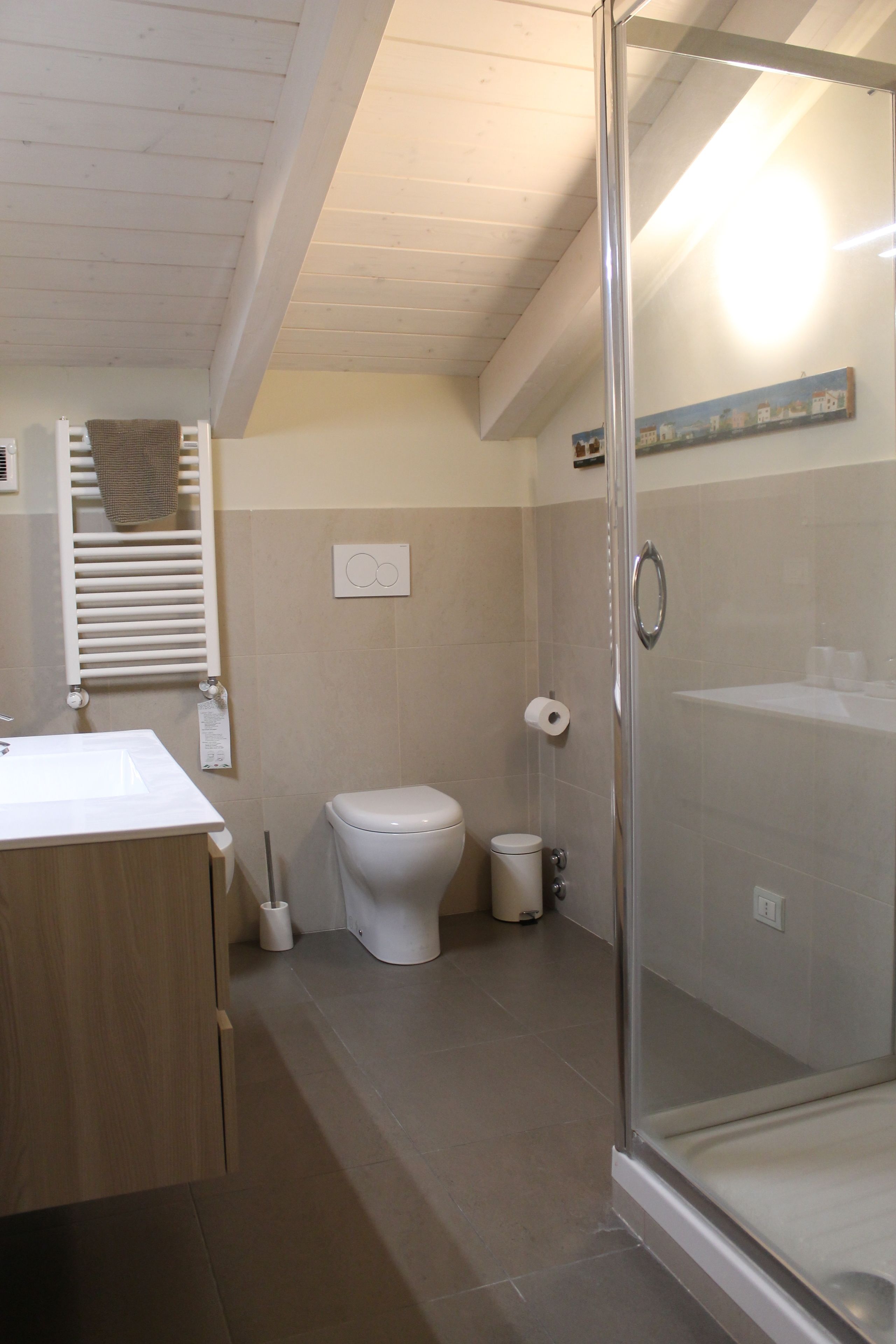 Ein modernes Badezimmer mit Glasdusche, Toilette und Waschbecken mit Handtuchhalter.